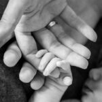 Neugeborenes Baby hält die Hand seiner Eltern